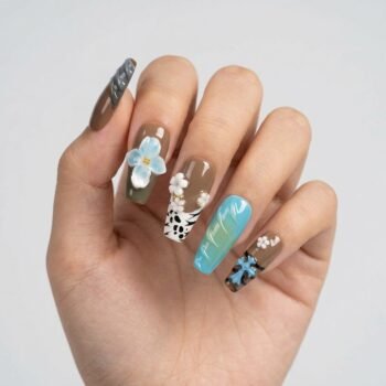 Waikiki Flora - Handmade coffin press-on nails with a tropical theme, featuring brown base tones, 3D blue and white flowers, cow print accents, and sea-foam blue textured details. | worn on hand 2 | So Does Nails